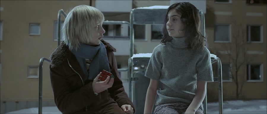 Lina Leandersson (Eli) sizes up Kåre Hedebrant (Oskar) and his Rubik's Cube in Let the Right One In (2008)