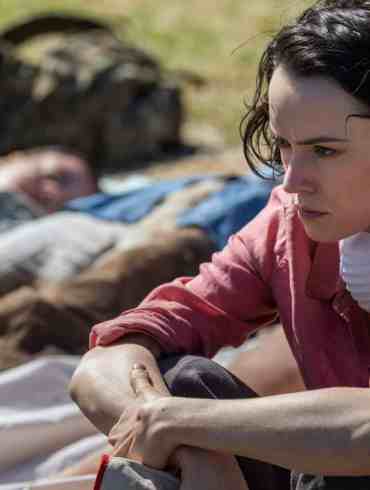 1. Woman in distress after a disaster, outdoors, with bodies lying on the ground.