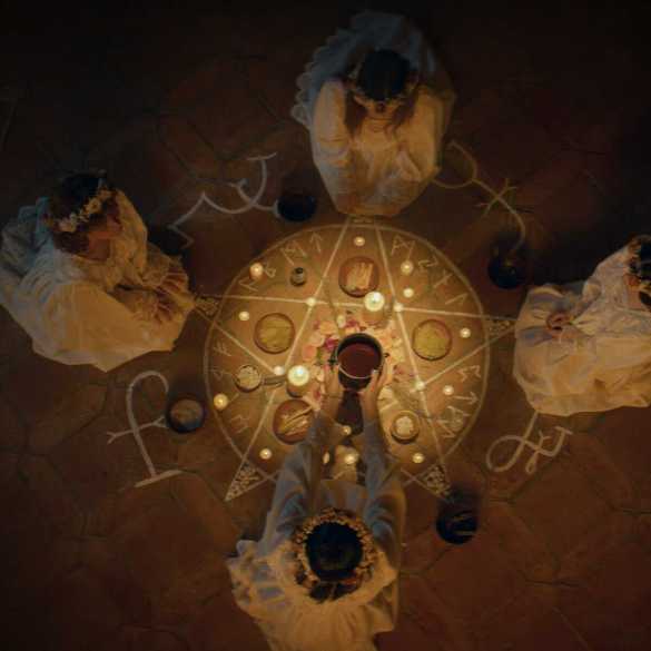 Witches performing a spooky ritual with candles and symbols on the floor.