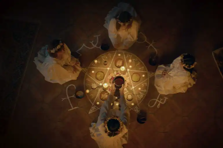 Witches performing a spooky ritual with candles and symbols on the floor.