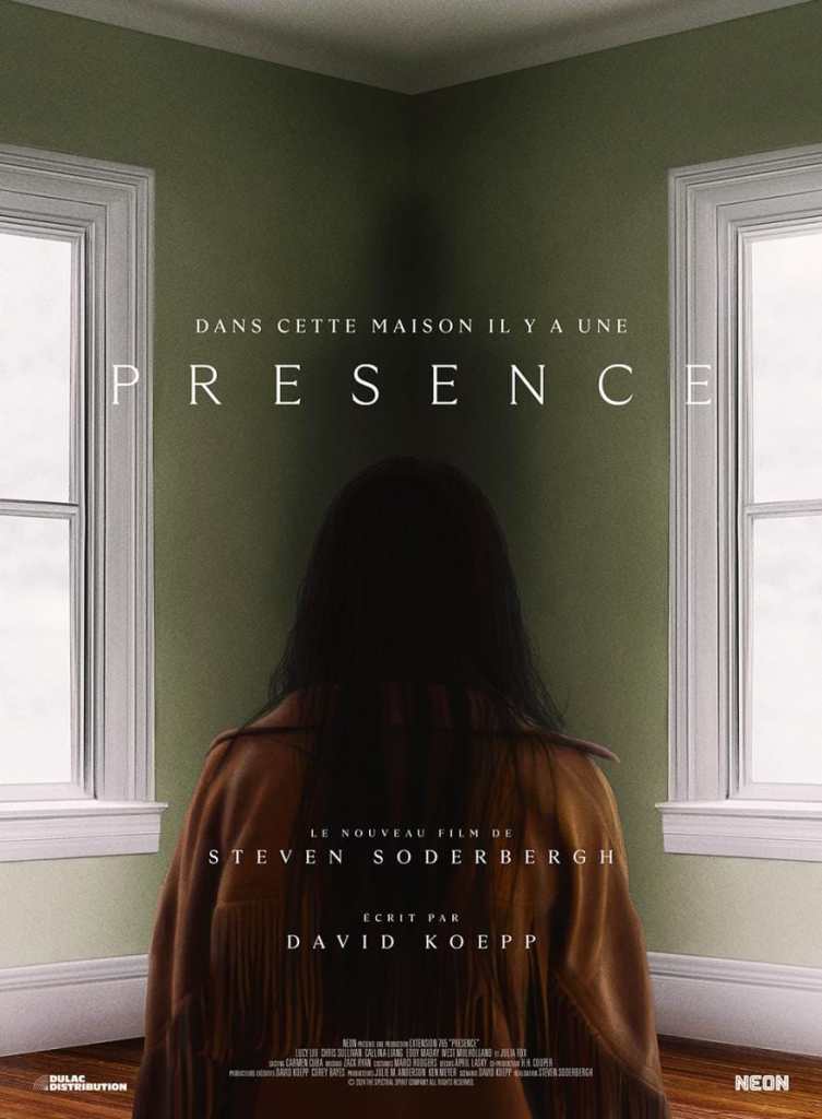 A woman with long hair standing in a green room with two windows, viewed from behind, promoting the.