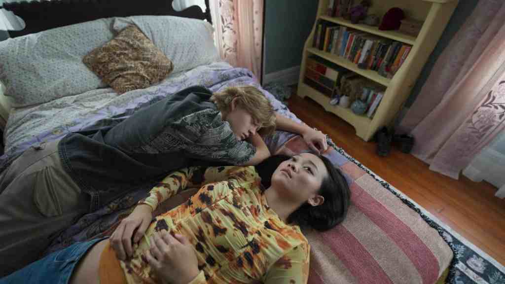 A woman and a man lying on the bed, appearing distressed and tense.