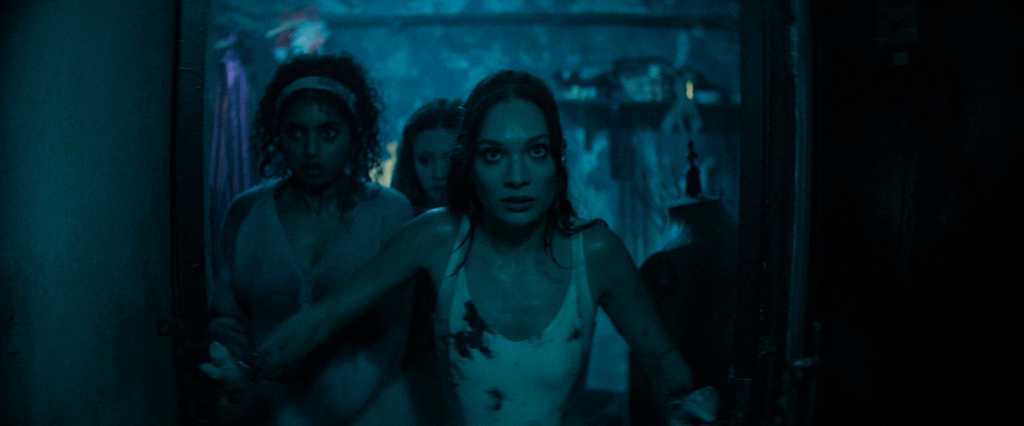 A haunting scene with women looking frightened in a dark, eerie setting.