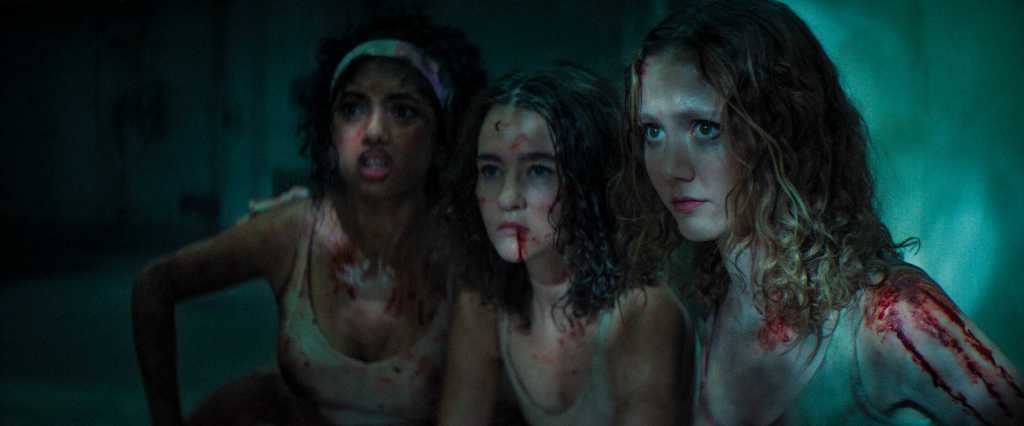 A haunting scene of three frightened women with bloodstains and distressed expressions.