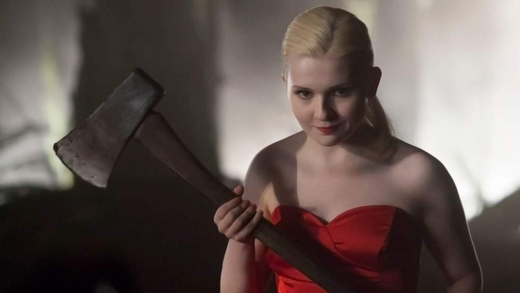 A woman holding an axe in a dark, eerie forest scene.