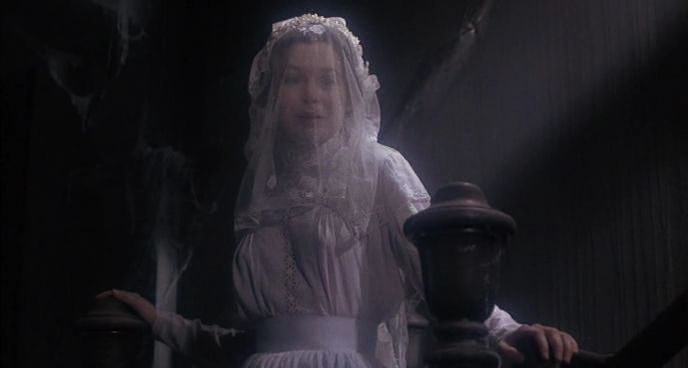 A woman in a white dress and veil with a ghostly appearance in a dark, eerie setting.