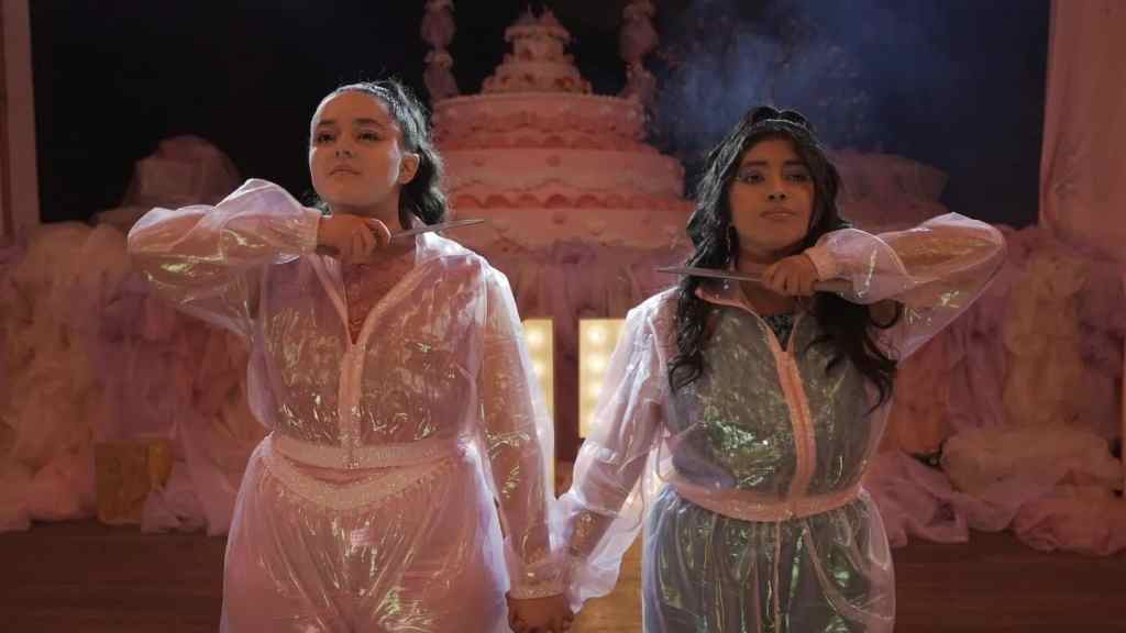 A woman and a girl in shiny, elegant dresses holding hands at a festive event.