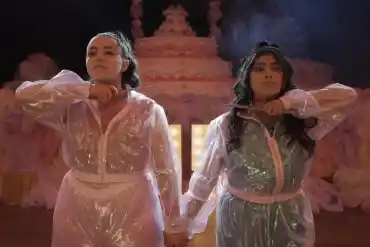 A woman and a girl in shiny, elegant dresses holding hands at a festive event.