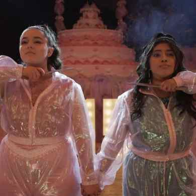 A woman and a girl in shiny, elegant dresses holding hands at a festive event.