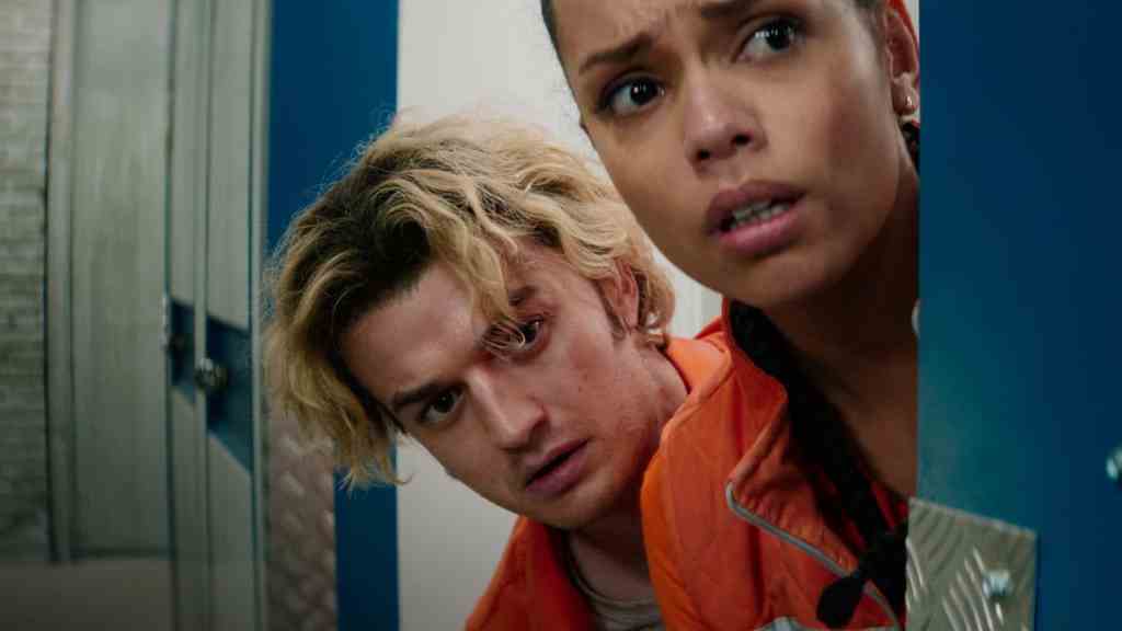 A young woman and a young man peering around a locker in a tense, suspenseful scene from Cold Storag.
