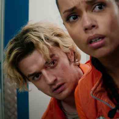 A young woman and a young man peering around a locker in a tense, suspenseful scene from Cold Storag.