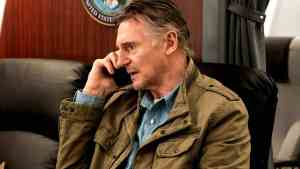 A man talking on the phone in an office setting, serious expression.