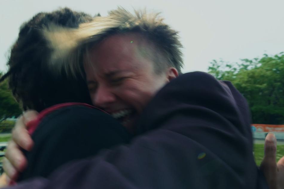 A heartbreaking hug between two distressed individuals outdoors.