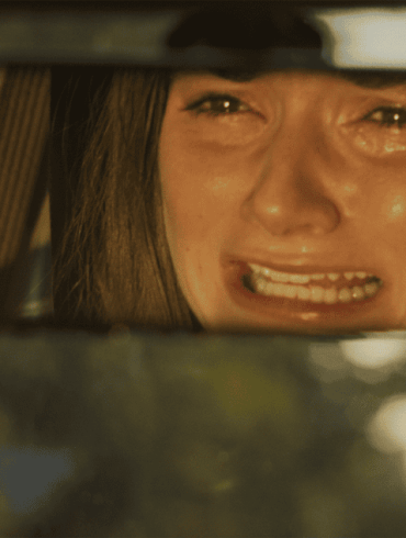 A woman with a distressed expression looking through a rearview mirror.