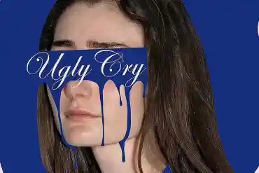 A woman with a distressed expression, partially covered by a blue sign reading "Ugly Cry" with dripp.