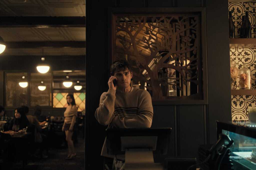 A mysterious man talking on the phone in a dimly lit restaurant.