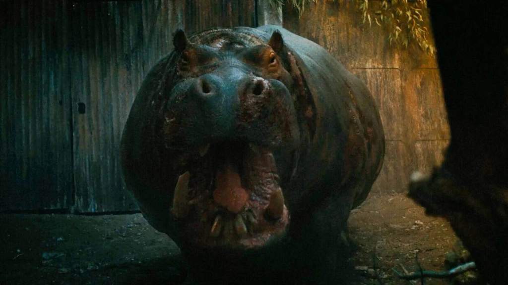 A hippo with an open mouth in a dark, jungle-like setting.