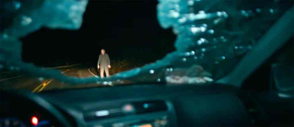 A haunting figure standing in the middle of a dark, deserted road at night.