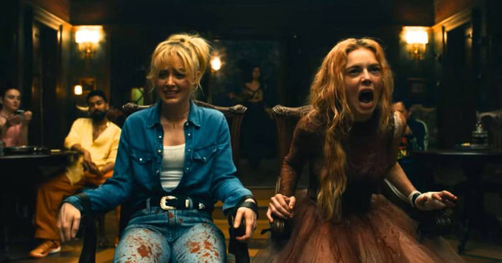 A woman with long blonde hair screams in terror during a tense scene in a dimly lit room.