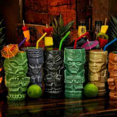 A colorful collection of tiki mugs with tropical drinks and umbrellas at Crypticon Seattle 2026.