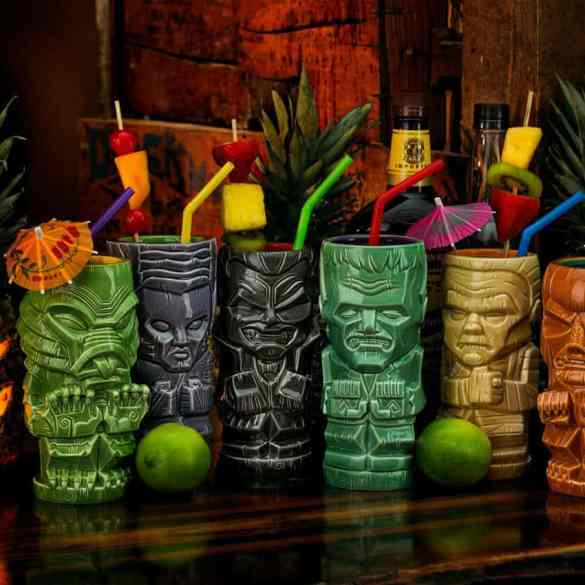 A colorful collection of tiki mugs with tropical drinks and umbrellas at Crypticon Seattle 2026.