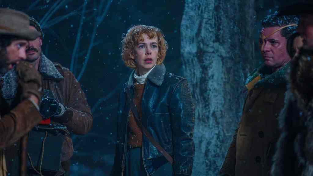 A woman with curly hair in a rainy, dark forest, looking frightened and surrounded by men in outdoor.