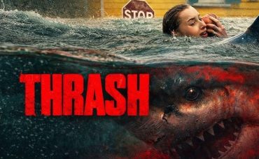 A woman swimming away from a large, menacing shark in murky water.