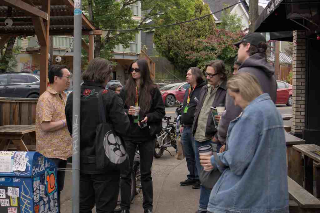 Group of people talking outside a cafe on a city street in daytime.