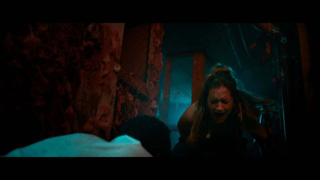 Woman screams in horror in a dark, eerie setting with red and blue lighting.
