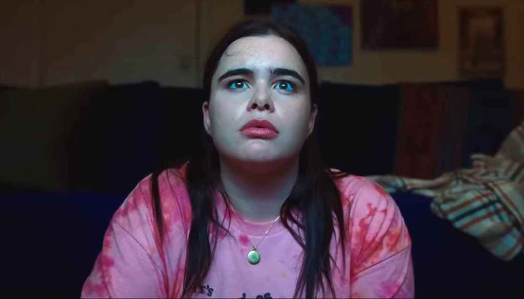 A woman with long dark hair and a pink tie-dye shirt looking surprised or scared.