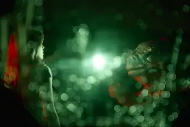 Futuristic scene with glowing green lights and a mysterious figure in darkness.