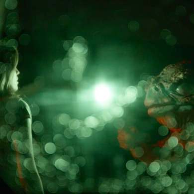 Futuristic scene with glowing green lights and a mysterious figure in darkness.