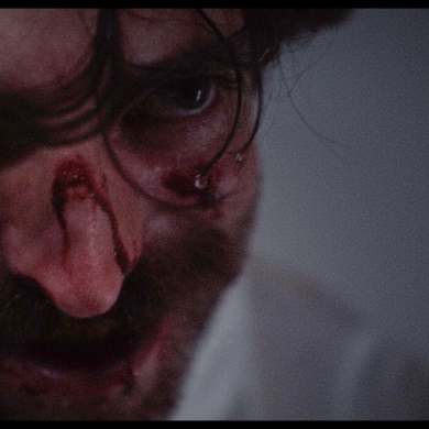 Close-up of a man with bloodied face and intense expression, horror scene from Dracula review.