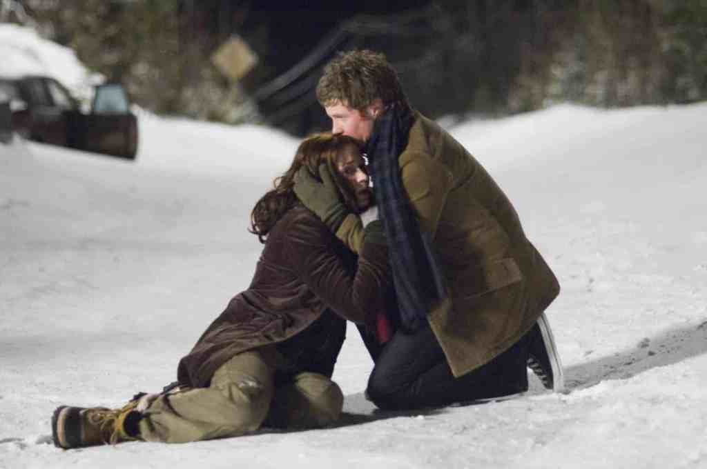 Two people in winter clothing comfort each other in a snowy landscape.