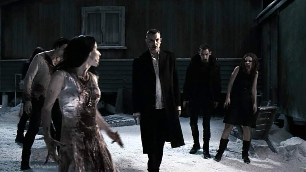 Dark, eerie scene with five people standing in snow outside a haunted house.