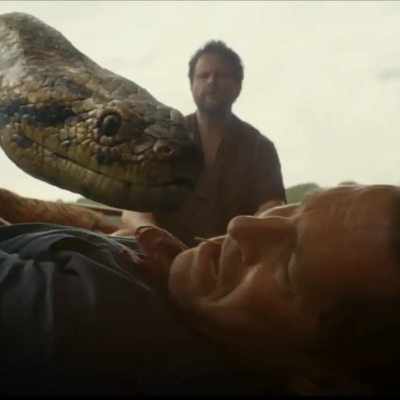 A man is attacked by a large snake in a tense scene from Anaconda (2025) review.