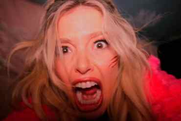 Woman with blonde hair screaming with a frightened expression and scratches on her face.