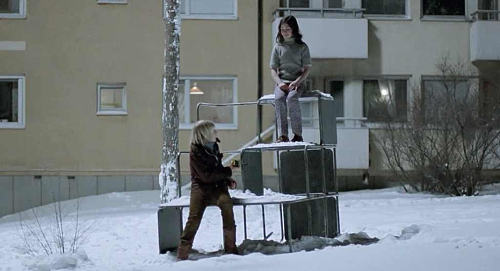 Children playing on snow-covered playground with a building in the background.