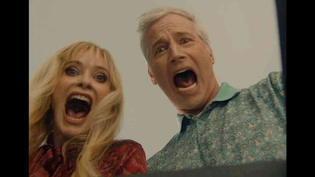 Two people with shocked expressions, mouth open wide, in a scene from a horror or thriller film.
