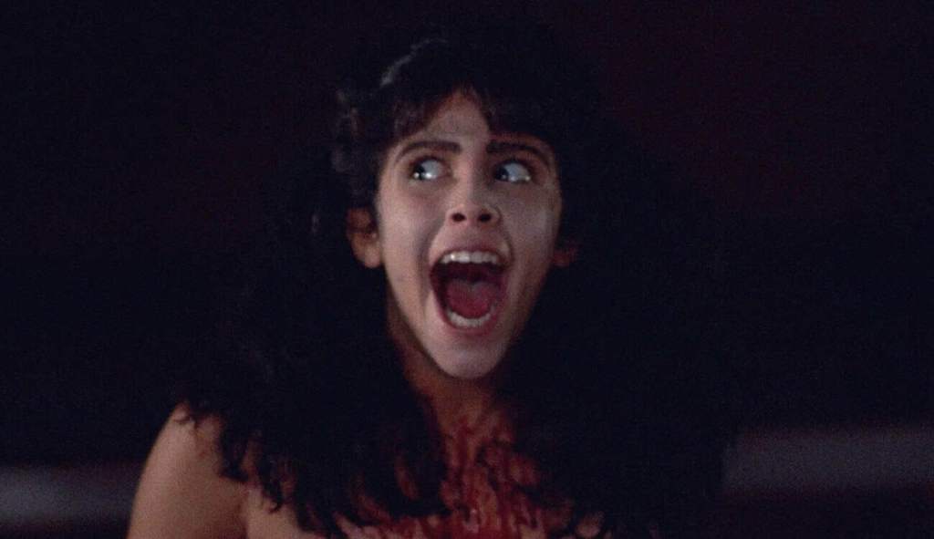 Scared woman with curly hair screaming in horror scene from Popcorn Frights.