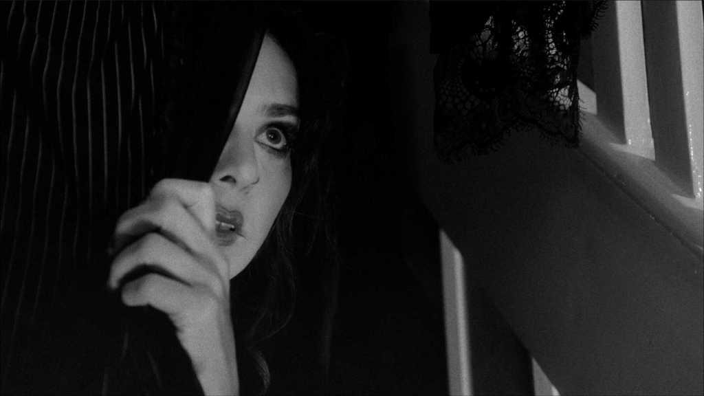 Woman with dark hair and intense gaze in black and white image.