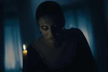 Eerie ghostly figure with glowing eyes in a dark room with candlelight.