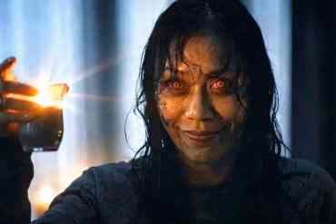 Evil Dead-inspired horror scene with a possessed woman holding a lit lighter.