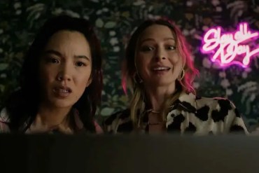Two women with surprised expressions in front of neon sign reading 'Show and Tell'.