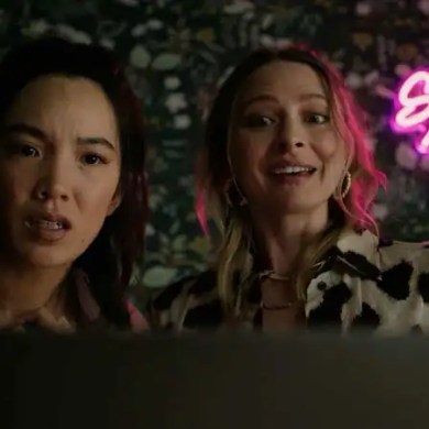 Two women with surprised expressions in front of neon sign reading 'Show and Tell'.