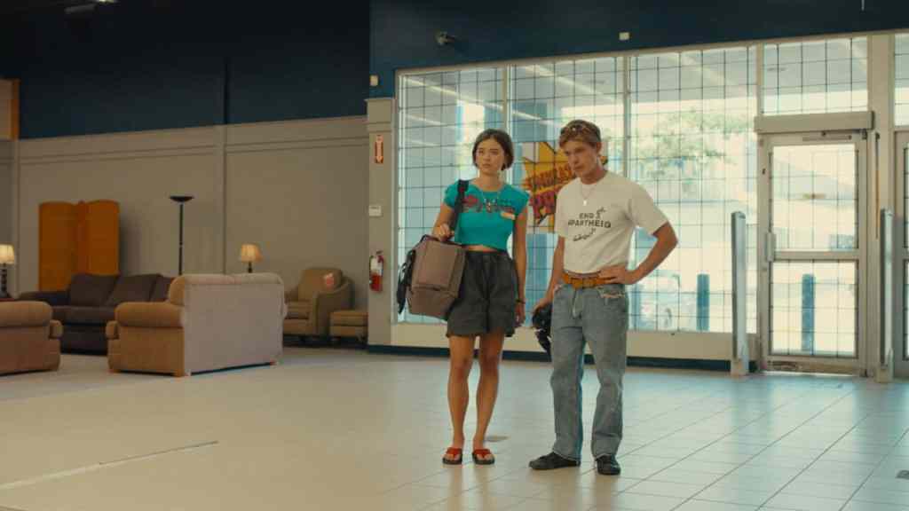Two young women stand in a spacious, modern lobby with large glass windows.