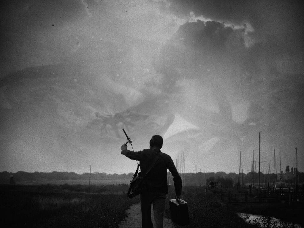 Silhouette of a person holding a sword and a bag against a stormy sky.