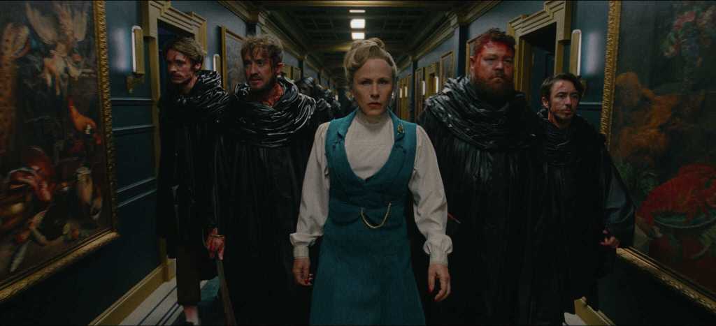 Group of five people walking down a hallway with paintings, intense expressions.