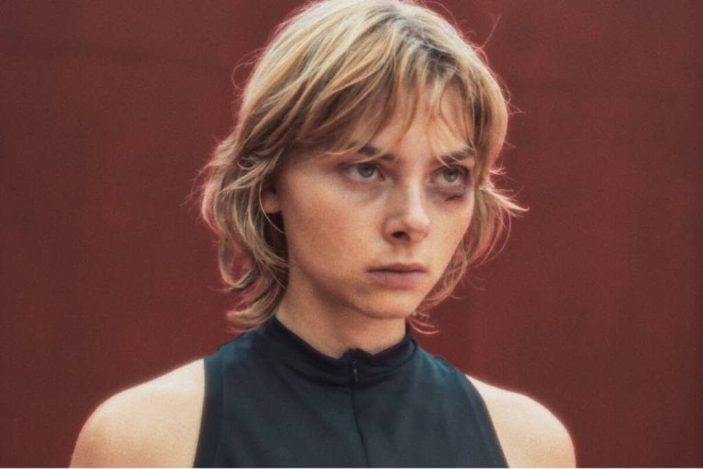 Close-up of a young woman with short blonde hair and intense expression.