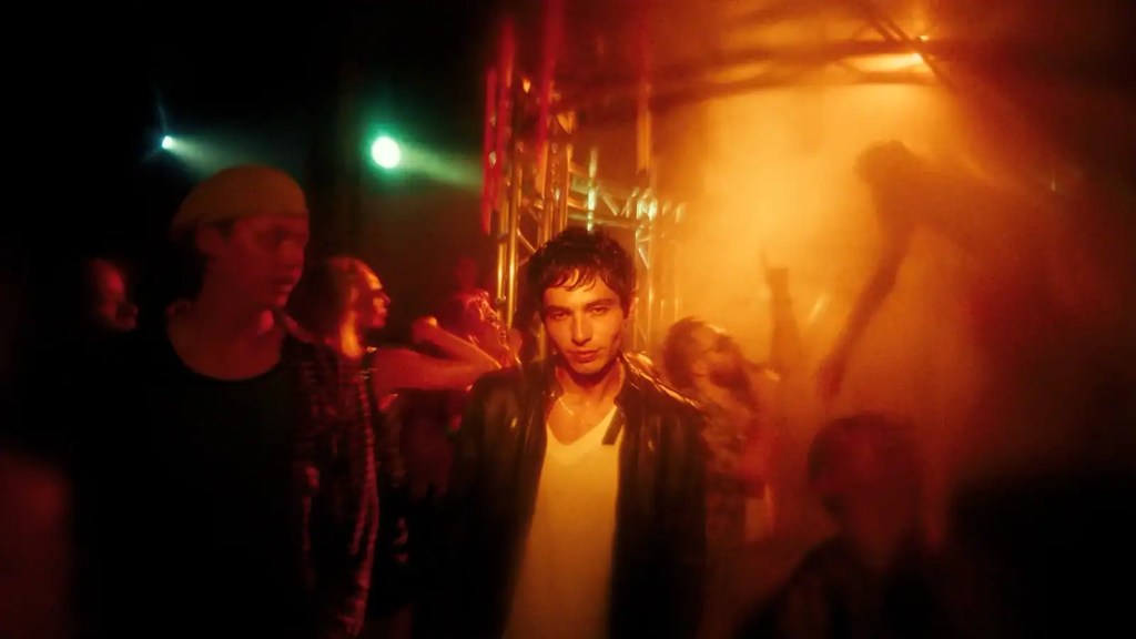 Young man with curly hair in a leather jacket at a horror film festival.